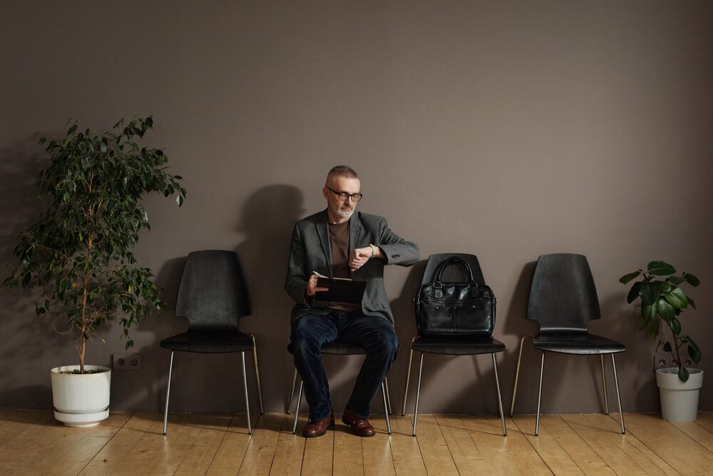A candidate checking his watch while waiting to be called into an interview